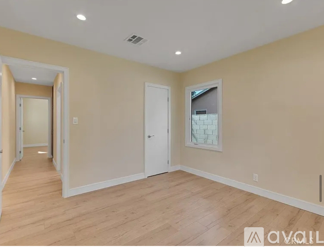 A spacious room with wooden flooring and white walls.