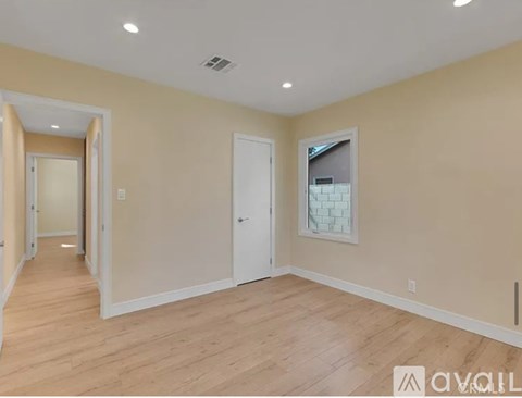 A spacious room with wooden flooring and white walls.