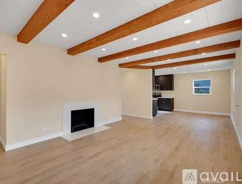 A spacious living room with a fireplace and wooden beams on the ceiling.