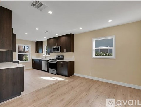 A spacious kitchen with dark brown cabinets and a white countertop.