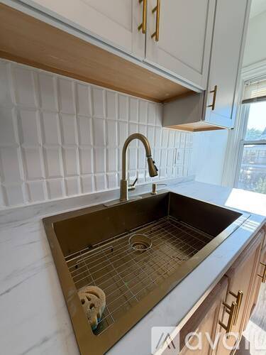 A kitchen with a stainless steel sink and a white tiled wall.