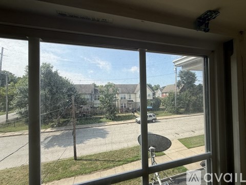 A view from inside a room looking out onto a street with houses and cars.