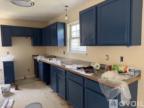 A kitchen under construction with blue cabinets and a countertop covered in plastic.