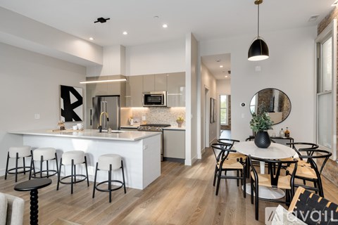 A modern kitchen with white countertops and a dining area with a round table and chairs.