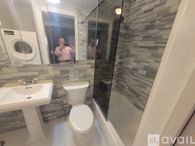 A man is taking a selfie in a bathroom with a mirror.