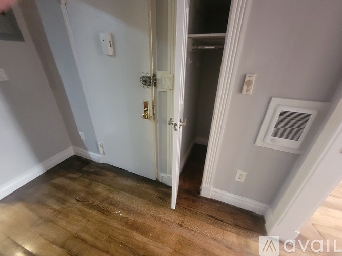 A room with a white door and a wooden floor.
