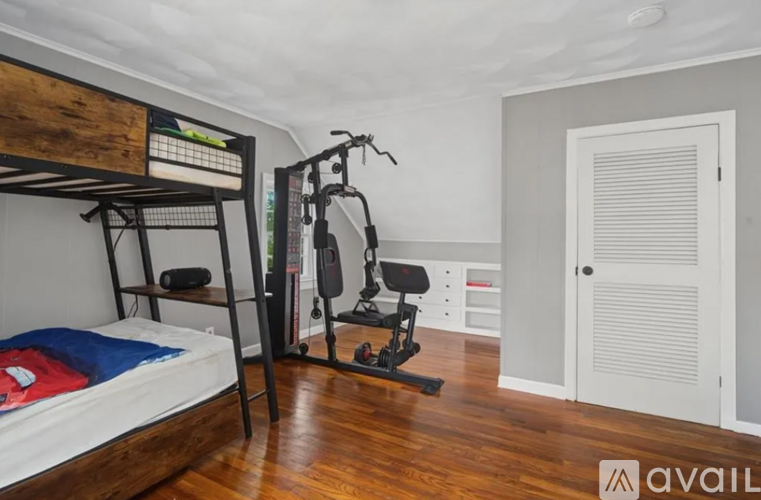 A room with a bunk bed, a chair, and a gym equipment.