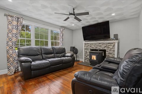 A living room with a black leather couch and a fireplace.