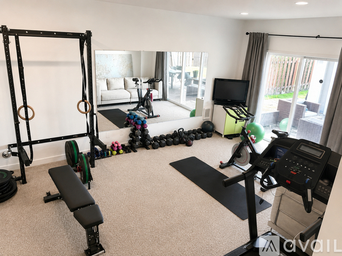 A home gym with a variety of equipment including a treadmill, weights, and a bench.