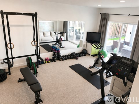 A home gym with a variety of equipment including a treadmill, weights, and a bench.