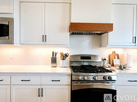 A modern kitchen with white cabinets and a stove top oven.