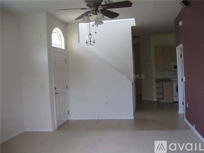A living room with a fan and a staircase.
