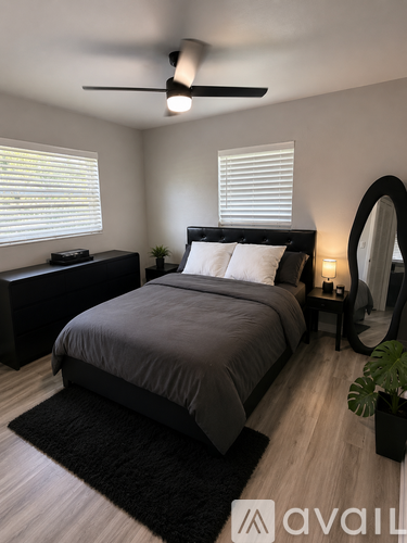 A bedroom with a bed, nightstand, and a plant.