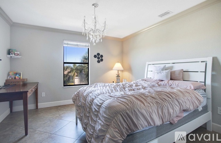 A bedroom with a large bed and a chandelier.