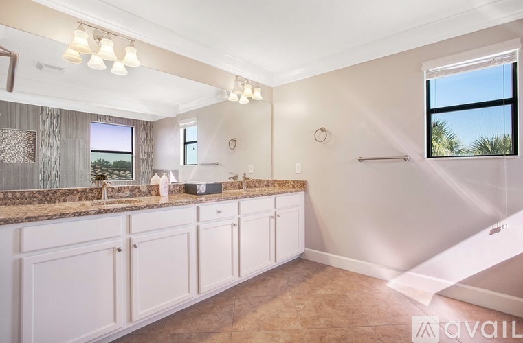 A kitchen with white cabinets and a marble countertop.