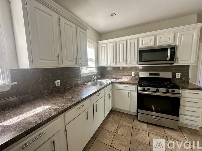 A kitchen with white cabinets and a tiled backsplash.