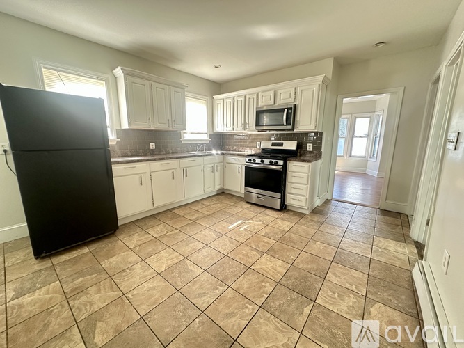A kitchen with a black fridge, microwave, and stove top oven.