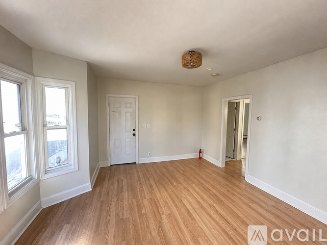 A room with wooden floors and white walls, with a door on the right side.