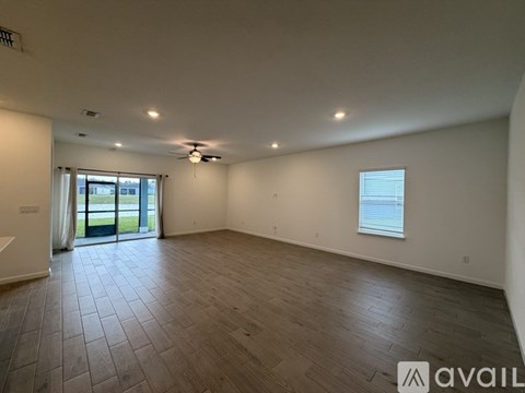 A spacious room with wooden flooring and a ceiling fan.