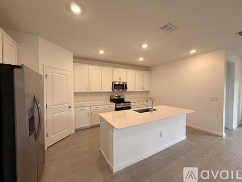 A kitchen with white cabinets and a black refrigerator.