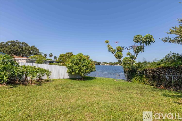 A grassy area with a body of water in the distance and a house on the left.