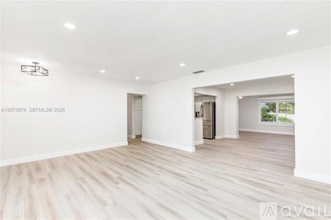 A spacious room with wooden flooring and white walls.
