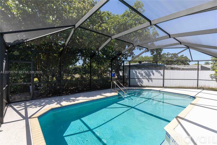 A pool under a white canopy with trees in the background.