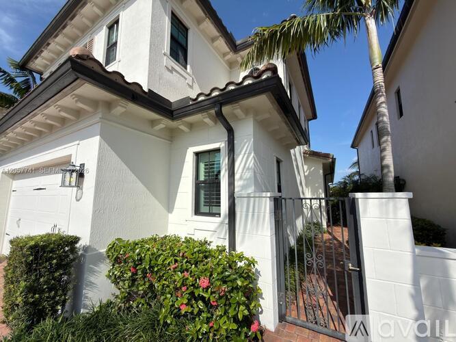 A white house with a black gate and a palm tree in front.