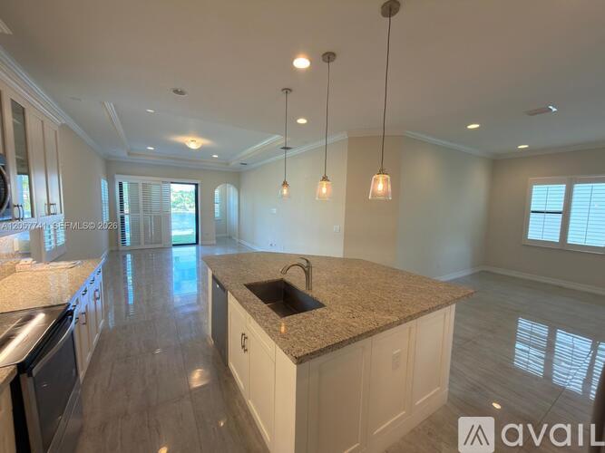 A kitchen with a granite countertop and pendant lights.