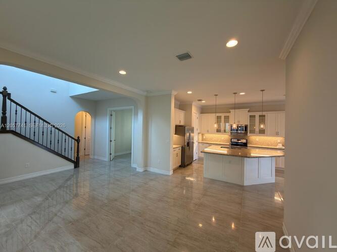 A spacious kitchen with a breakfast bar and a staircase with a black railing.
