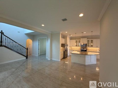 A spacious kitchen with a breakfast bar and a staircase with a black railing.