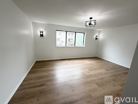 A room with wooden flooring and a window showing a city view.