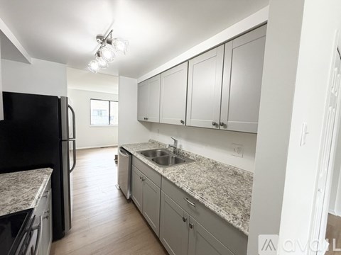 A kitchen with a black fridge and a granite counter top.