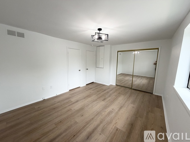 A spacious room with wooden flooring and white walls.