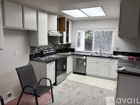 A kitchen with a black chair in front of it.