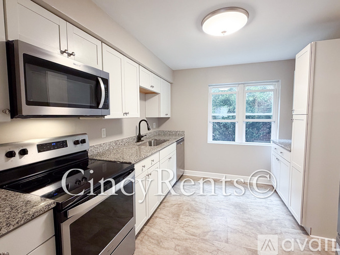 A kitchen with a black microwave above a stove and white cabinets.
