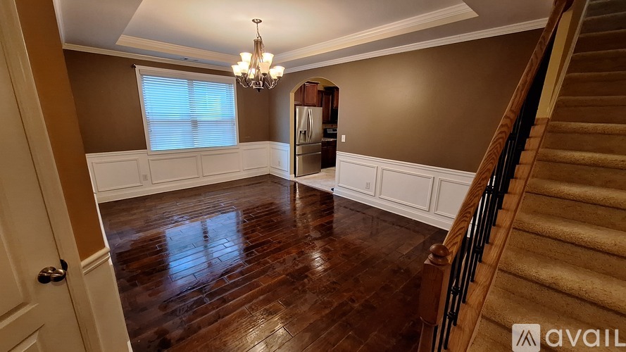 A spacious room with wooden floors and a staircase.