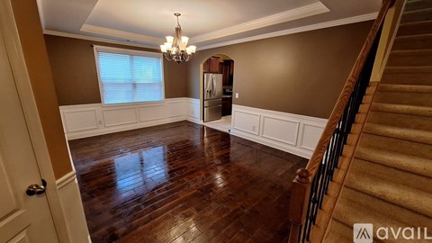 A spacious room with wooden floors and a staircase.