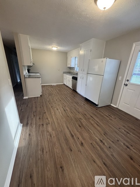 A kitchen area with white appliances and wooden flooring.