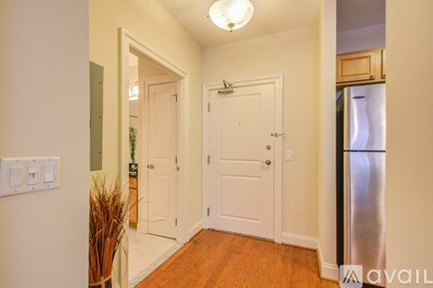 A kitchen with a refrigerator and a door leading to another room.