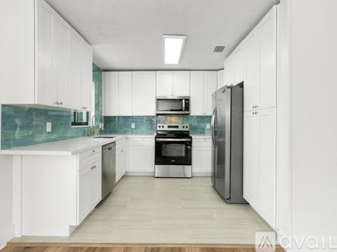 A modern kitchen with white cabinets and a wooden floor.