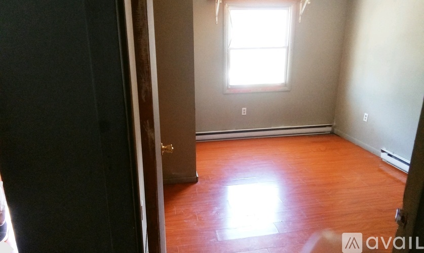 A room with wooden floors and a window letting in sunlight.