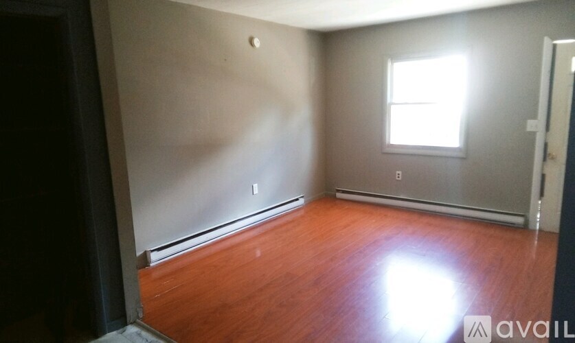A room with wooden floors and a window letting in sunlight.