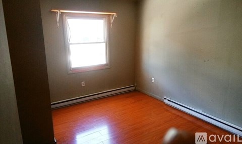 A room with a window and wooden floors is available for rent.