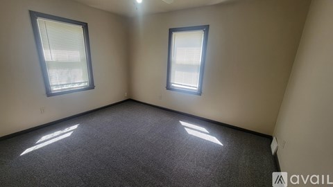 A room with two windows and carpeted floor.