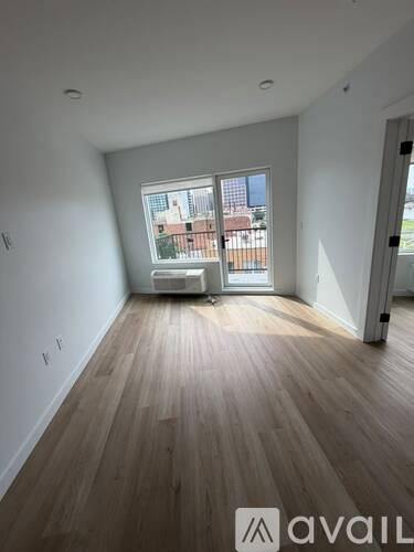 A room with wooden flooring and a large window overlooking a building.