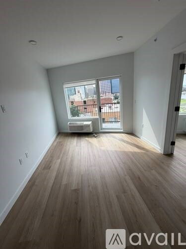 A room with wooden flooring and a large window overlooking a building.