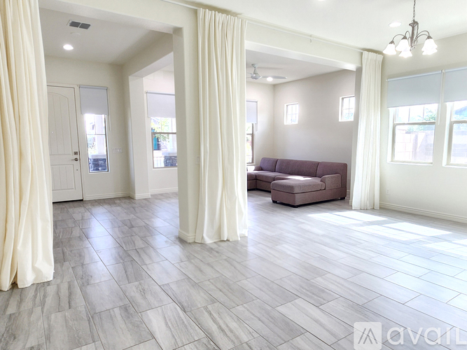 A living room with a grey sofa and white curtains.
