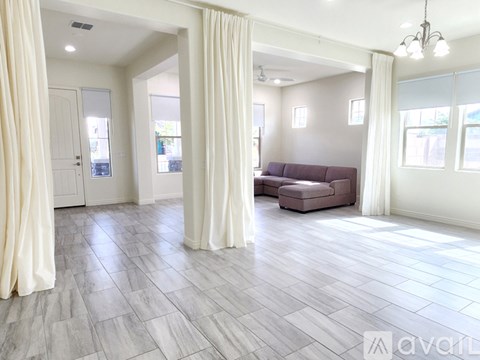 A living room with a grey sofa and white curtains.