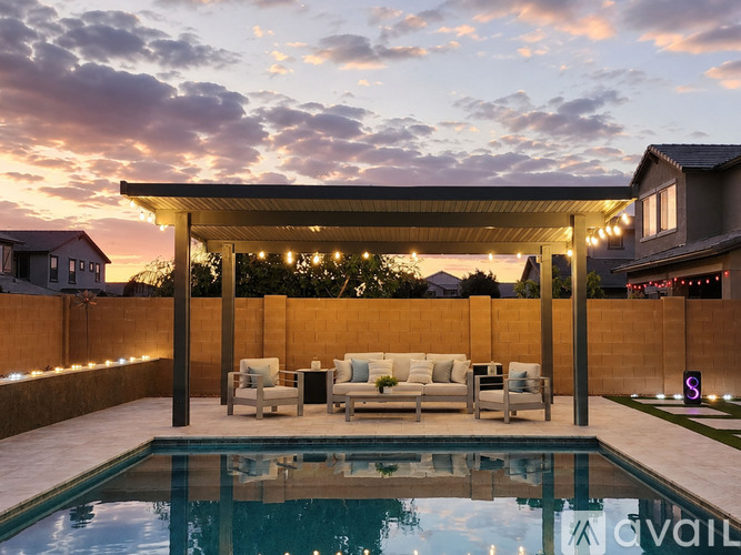 A pool with a white couch and chairs under a roof with lights.